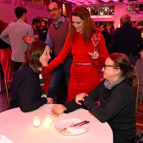 Candid photo of three women talking at a table. 