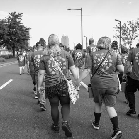 People marching in parade, back and white photo. 