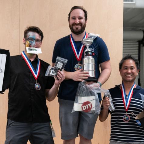 Men holding up awards. 