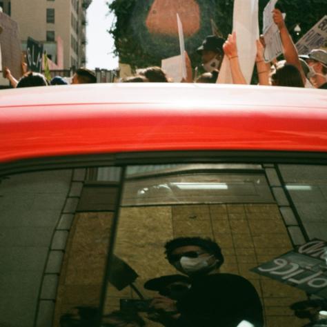 Reflection of a person in red car window. 