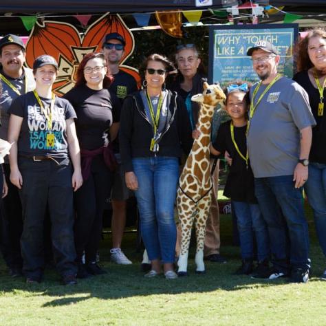 Group of people posing for photo with giraffe. 