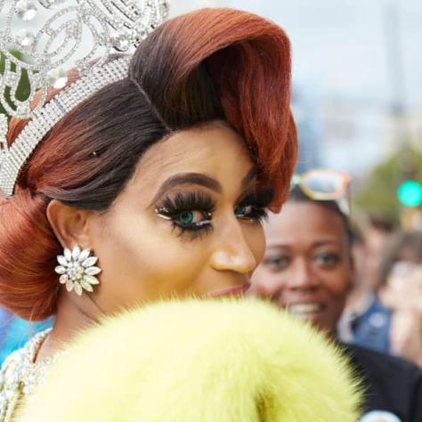 Drag queen posing for photo at parade. 