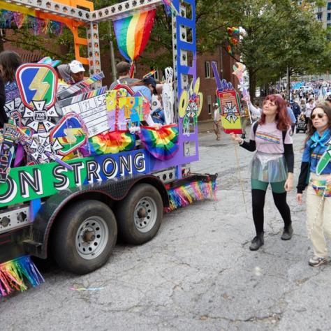 People standing next to pride float. 