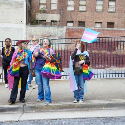 People standing on sidewalk with pride signs. 