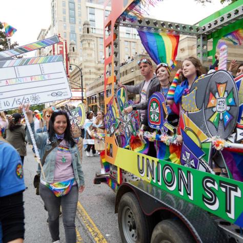 People marching next to float in pride parade. 