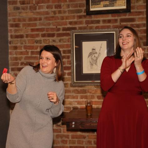 Candid photo of women clapping and holding red piece. 