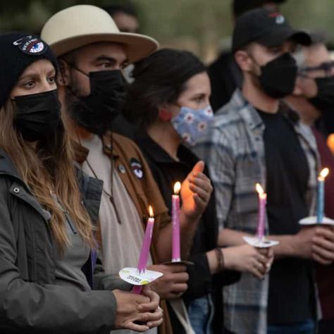 People standing outside with masks and candles. 