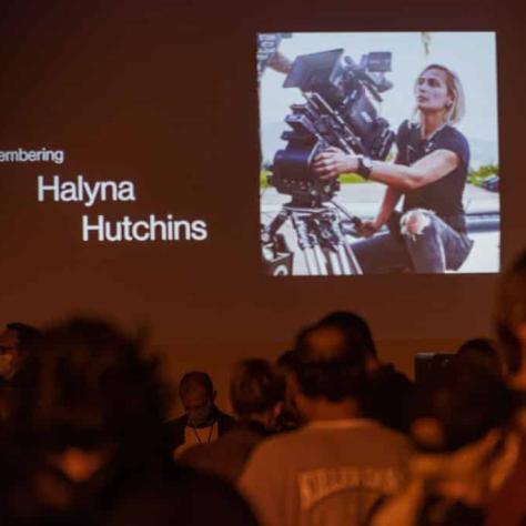 Photo of a woman on screen with a camera. 