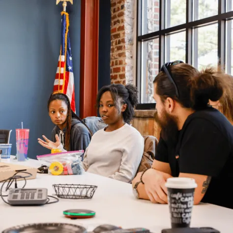 People sitting at conference table talking. 