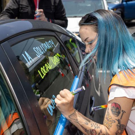 Woman writing on car window. 