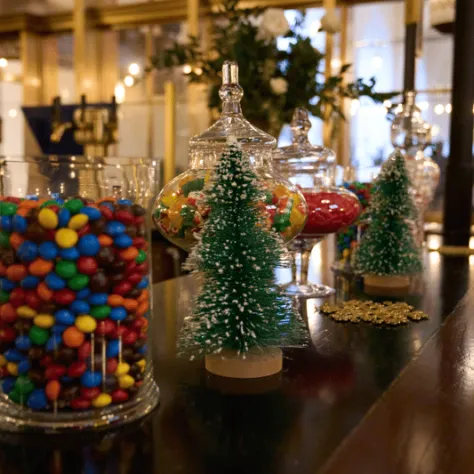 Jar of candy and two mini Christmas tree decorations. 