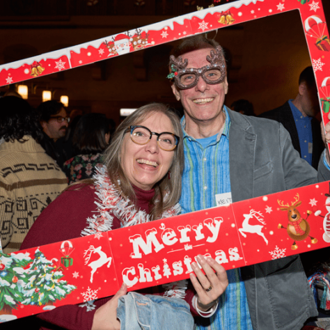 People posing for photo together in Merry Christmas frame. 