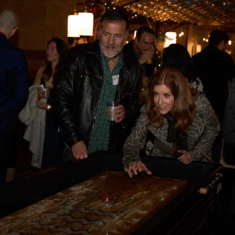 People playing shuffleboard on a table. 