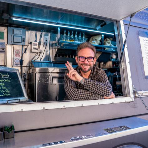 Man in food truck giving peace symbol. 