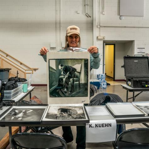 Person posing with photo at yard sale. 