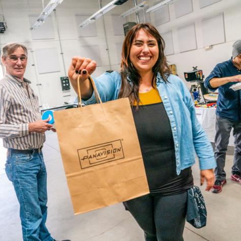 Woman with bag posing for photo at yard sale. 