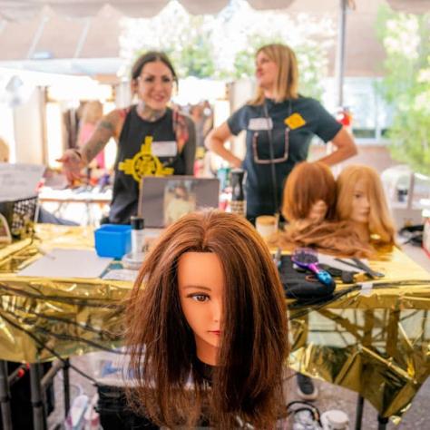 Photo of doll head and two people standing at a table. 