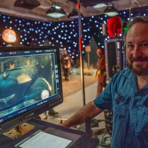 Man posing for photo in front of screen. 