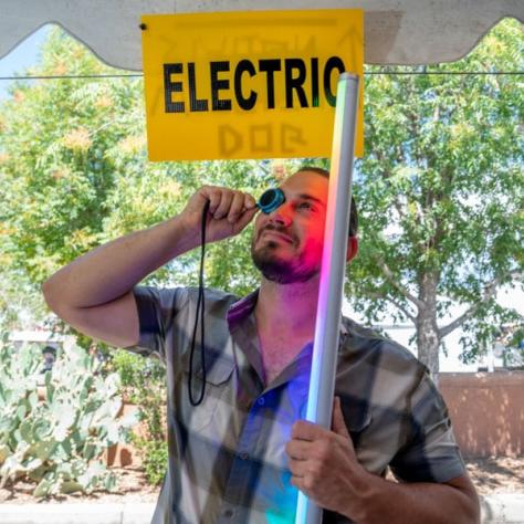 Man looking at something under yellow electric sign. 