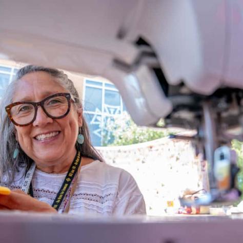 Woman smiling for photo through sewing machine. 