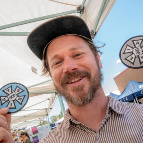 Man posing for photo with patches in his hands. 