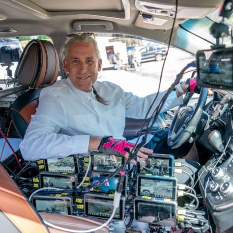 Man in car with gear, posing for photo. 