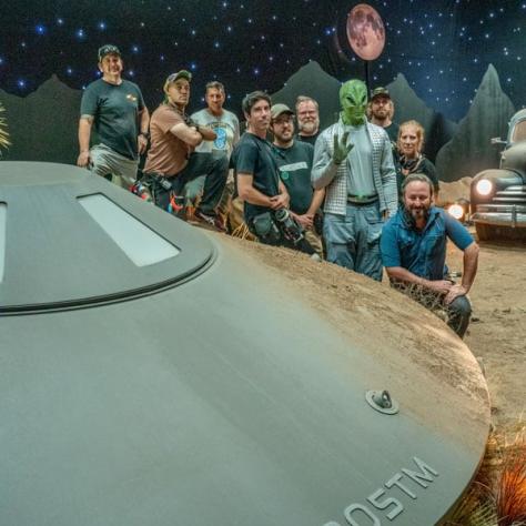 People posing with spaceship on set. 