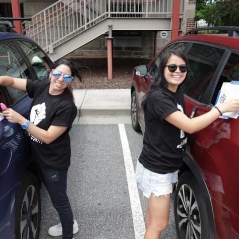 Two women putting signs on their cars. 