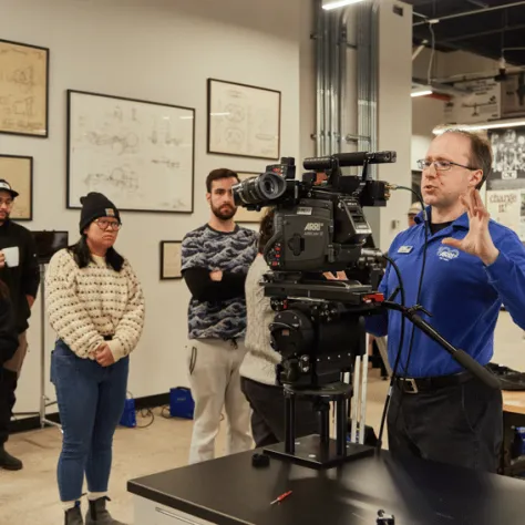 Man working with camera while people watch. 