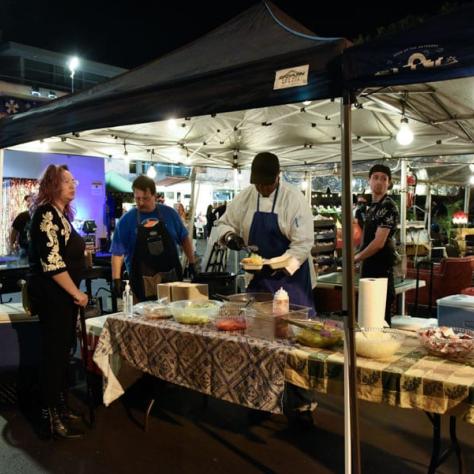 People serving food under a tent. 