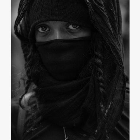 Black and white photo of someone in hoodie and mask. 