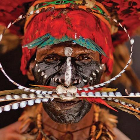 Close up of person with traditional village garb and painted face. 