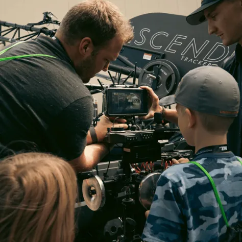 Man and boy looking into a camera viewer. 