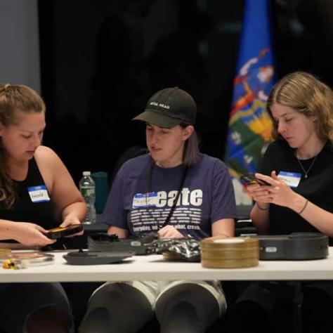 Three people sitting at a table working with film. 