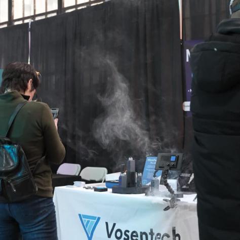 Vendor table and people standing. 