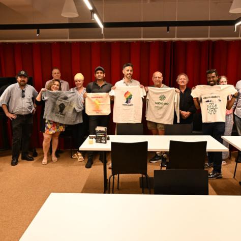 Group photo with people holding signs and t-shirts. 