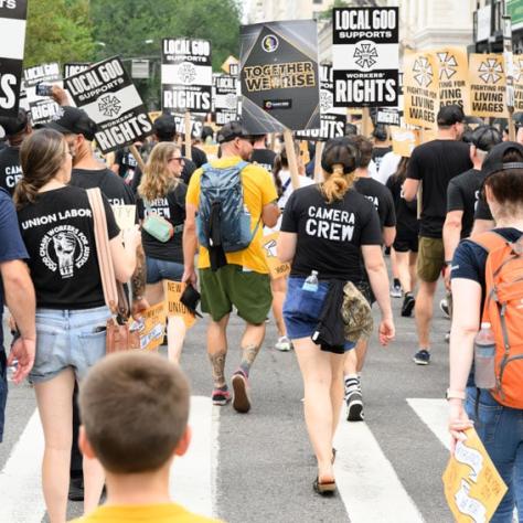 Back of people marching with signs. 