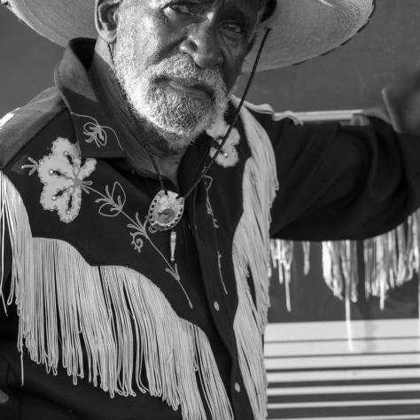 Black and white photo of man with cowboy outfit. 