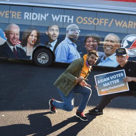 People posing with a sign in front of a bus. 