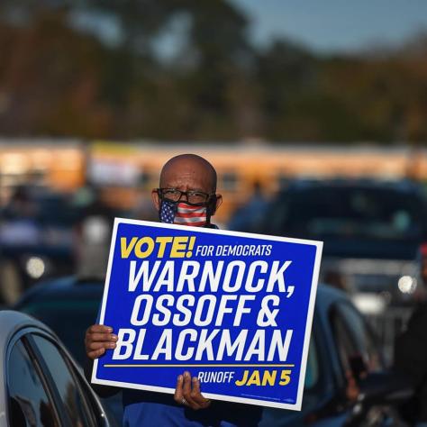 Man holding a Warnock sign. 