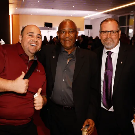 Three men posing for photo together. 