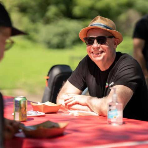 Man smiling at a table outside. 