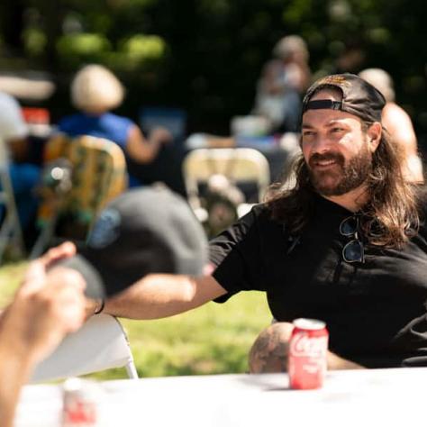 Man talking at a table outside. 