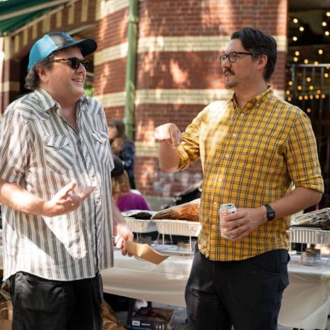 Two men talking an laughing outside. 