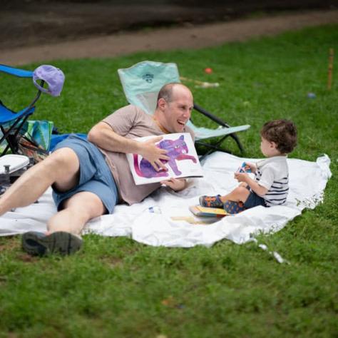 Man and child laying on picnic blanket. 