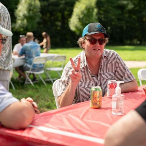 Man sitting at table giving peace sign. 