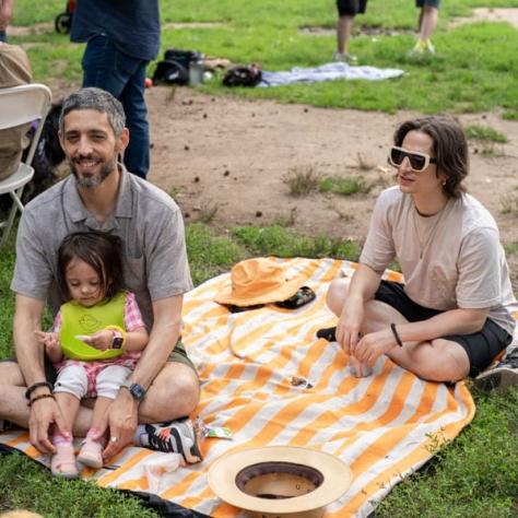 Family sitting on picnic blanket. 