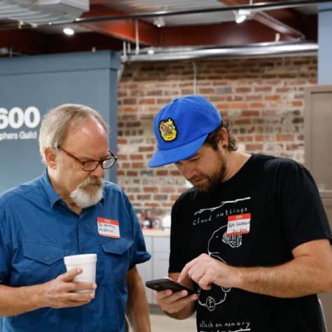 Two men looking at a phone. 