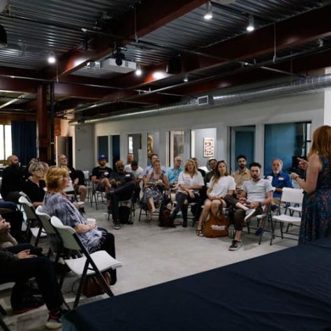 People sitting in an audience looking at two people. 