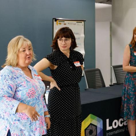 Women talking at the front of the room. 